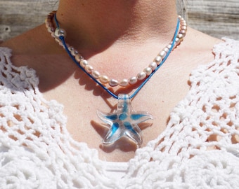 May include: A blue and white glass starfish pendant necklace with a pearl and blue cord necklace layered on top.