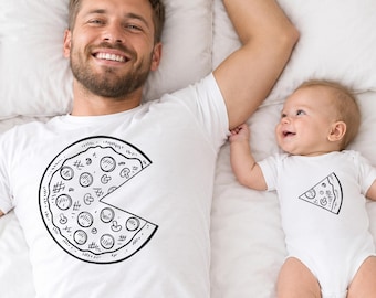 May include: A white short-sleeved t-shirt featuring a large black line-art graphic of a pizza with one slice missing, and a white baby bodysuit featuring a matching black line-art graphic of a single pizza slice.