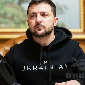 Może przedstawiać: Mężczyzna w czarnym swetrze z kapturem z nadrukiem "I'm Ukrainian" w kolorze białym na przodzie.
