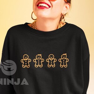 Może przedstawiać: Czarna bluza z złotym łańcuszkiem i wzorem czterech piernikowych ludzików w rzędzie.