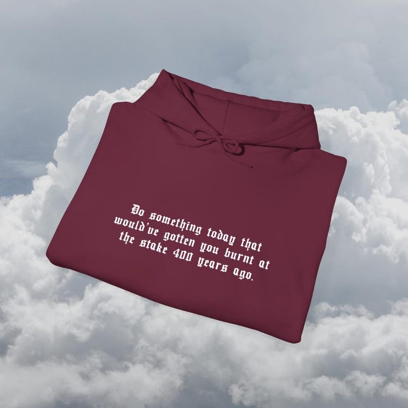 Peut inclure: Un sweat &agrave; capuche bordeaux avec une capuche &agrave; cordon et une poche avant. Le sweat &agrave; capuche porte le texte blanc : "Faites quelque chose aujourd'hui qui vous aurait fait br&ucirc;ler sur le b&ucirc;cher il y a 400 ans."