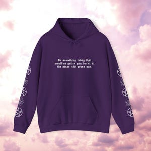 Peut inclure: Un sweat &agrave; capuche violet avec une poche avant et une capuche &agrave; cordon. Le texte "Do something today that would've gotten you burnt at the stake 400 years ago" est imprim&eacute; sur le devant. Des pentagrammes blancs et des motifs floraux ornent les manches.