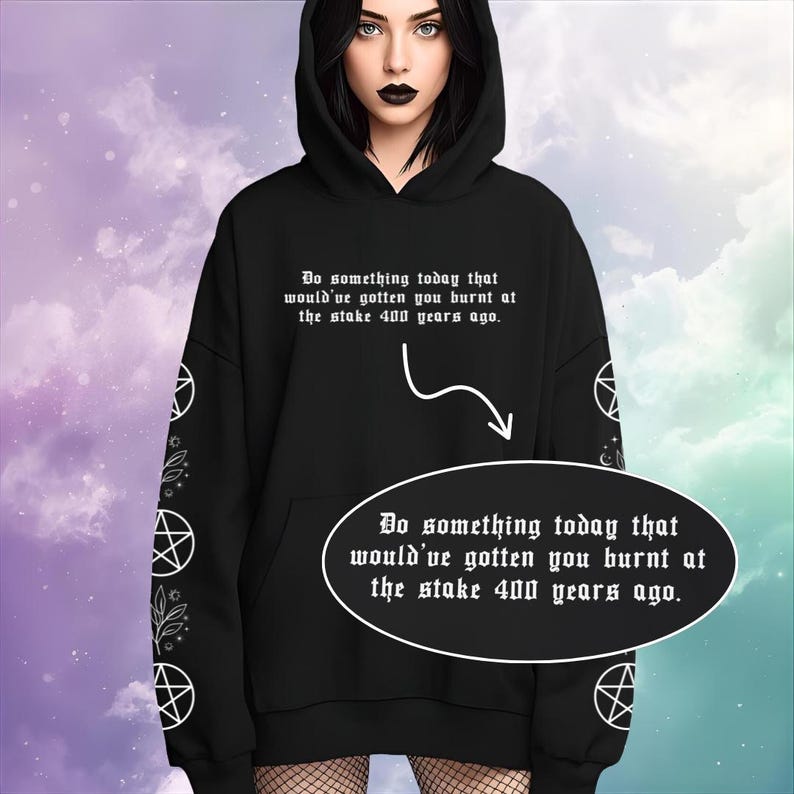 Peut inclure: Sweat &agrave; capuche noir avec texte blanc : "Faites quelque chose aujourd'hui qui vous aurait fait br&ucirc;ler sur le b&ucirc;cher il y a 400 ans." Motifs blancs de pentagrammes et de fleurs sur les manches.