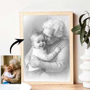 以下が含まれることがあります： 年配の人が抱きしめている赤ちゃんの、額装された白黒鉛筆スケッチ。赤ちゃんは笑顔で、年配の人は眼鏡をかけています。フレームは明るい色の木材です。同じシーンの小さなカラー写真が左下隅にあります。