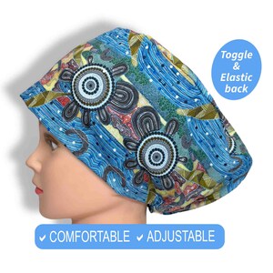 May include: A blue patterned scrub cap with a toggle and elastic back. The cap features a repeating design of stylized floral shapes in shades of blue, brown, red, and yellow. Text on the image reads "Comfortable" and "Adjustable."