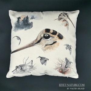 Peut inclure: Un oreiller blanc avec une illustration aquarelle d'un bécasseau. L'illustration présente plusieurs vues de l'oiseau, y compris un gros plan de son œil et de son bec. L'oreiller est décoré d'une scène de forêt en arrière-plan.