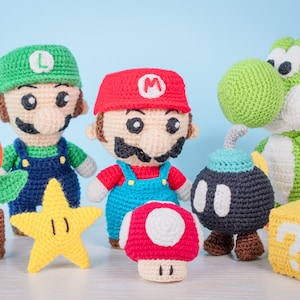 May include: Crocheted plush toys of characters from the Super Mario video game series. The characters include Mario, Luigi, Yoshi, a bomb, a star, a mushroom, and a question block.
