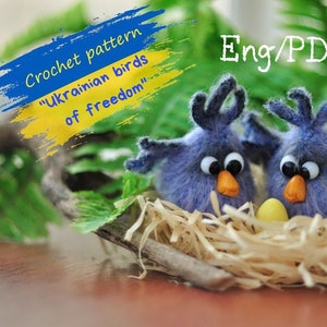 May include: Crochet pattern for two blue birds in a nest with an egg. The pattern is titled "Ukrainian birds of freedom" and is available in English and PDF format.