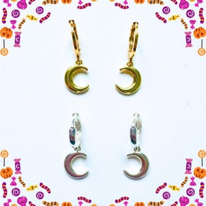 May include: Gold and silver crescent moon earrings. The earrings have a small hoop design with a crescent moon charm. The gold earrings are at the top, and the silver ones are at the bottom. The background is white with a Halloween-themed border.
