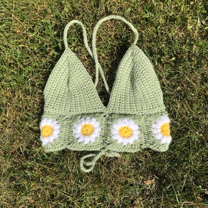 May include: A green crocheted halter top with a daisy design. The top has a tie closure at the back.