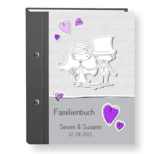 May include: A gray photo album with a black spine and a cover featuring a cartoon bride and groom with purple hearts. The text on the cover reads "Familienbuch" "Seven & Susan" "12.08.2021".