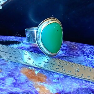 May include: A silver ring featuring a smooth, teardrop-shaped green stone set in a bezel. The ring band has a textured finish with small star cutouts. A stainless steel ruler is positioned alongside, showing the stone width is about 0.75 inches.