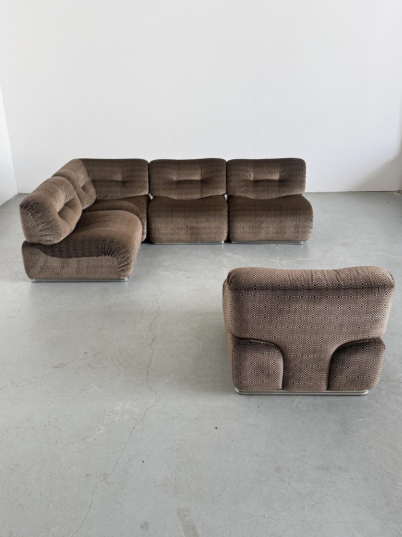 May include: A brown modular sofa and ottoman set. The sofa has a corner configuration with multiple cushioned sections. The ottoman has a matching patterned fabric. The furniture sits on a silver metal base.