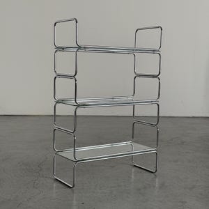 Peut inclure: Une étagère à quatre niveaux composée de cadres en métal tubulaire chromé poli avec trois étagères en verre transparent. La structure présente un design rectangulaire arrondi continu qui forme les côtés et les supports de chaque niveau.