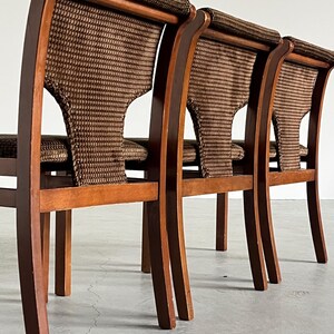 May include: Three wooden chairs with woven backs and seats. The chairs have a curved design with a dark brown finish. The woven material is a mix of brown and tan.