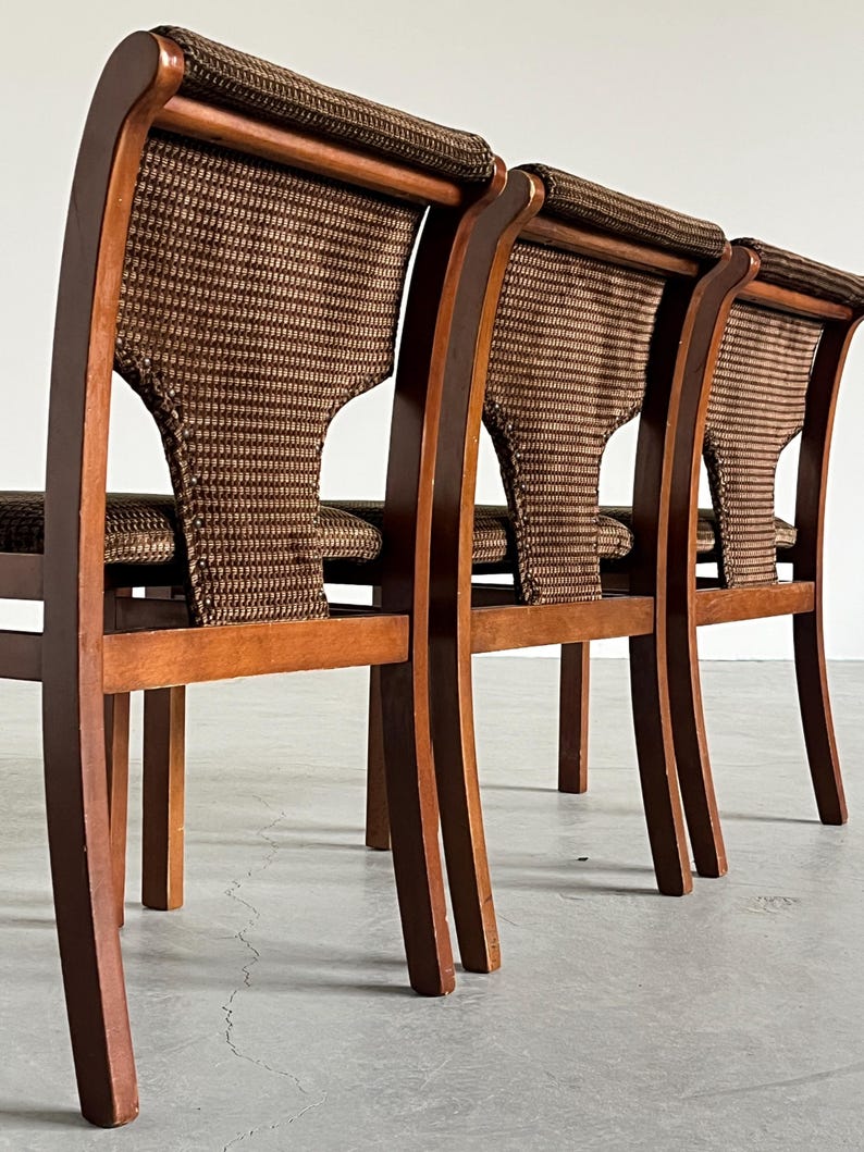 May include: Three wooden chairs with woven backs and seats. The chairs have a curved design with a dark brown finish. The woven material is a mix of brown and tan.