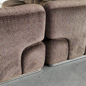 May include: A brown and white patterned sofa with a rounded design. The sofa has a checkered pattern on the cushions and a solid brown fabric on the back. The sofa sits on a silver metal base.