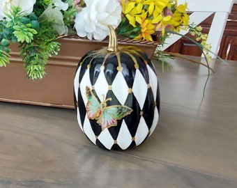 May include: Black and white pumpkin with a gold and green butterfly design. The pumpkin is decorated with a diamond pattern.