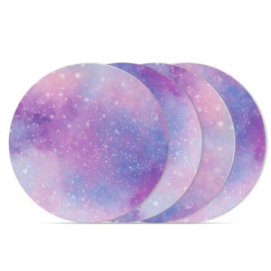 Peut inclure: Ensemble de quatre sous-verres ronds à thème galaxie, de couleur violette et bleue. Les sous-verres ont un effet aquarelle avec des points blancs.