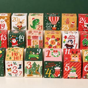 May include: A set of twenty-four square cardboard boxes arranged in a grid, each featuring unique Christmas-themed illustrations and a large number from one to twenty-four, including images of Santa, reindeer, snowmen, and festive holiday patterns.
