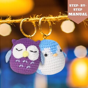May include: Two crocheted animal keyrings, an owl and a penguin, hanging from a gold key ring. The owl is purple with white eyes and a yellow beak. The penguin is blue and white.