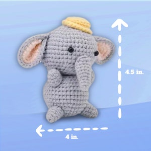 Op de afbeelding: Een grijs gehaakt olifantenspeelgoed met een gele hoed. Het speelgoed is 4,5 inch hoog en 4 inch breed.