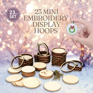 May include: A set of 23 mini embroidery display hoops. The wooden hoops are in various sizes and shapes, with a small cross-stitch ornament held by a hand. The text "23 pc. SET" and "23 MINI EMBROIDERY DISPLAY HOOPS" are visible.