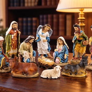 May include: A nativity set featuring hand-painted figurines of the Holy Family, an angel, three wise men, a shepherd with a lamb, a cow, a donkey, and a sheep. The figures are depicted in colorful robes and are arranged on a wooden surface.