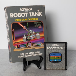 May include: A vintage Atari 2600 video game cartridge for Robot Tank by Activision. The box art features a futuristic tank with a red laser beam. The cartridge is gray with a black label and the same image as the box.