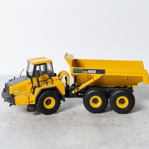 May include: A yellow toy dump truck with a black cab and black wheels. The truck has "HK 400" printed on the side.