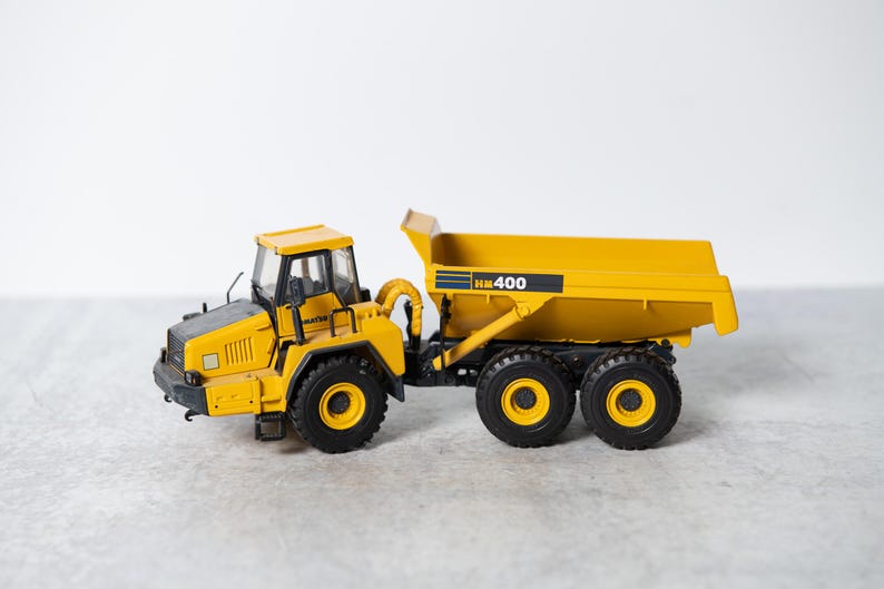 May include: A yellow toy dump truck with a black cab and black wheels. The truck has "HK 400" printed on the side.