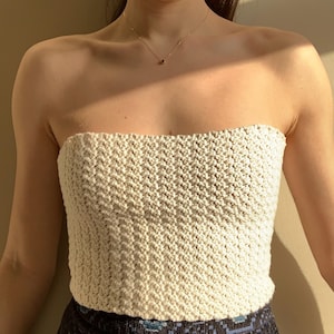 May include: A white crocheted tube top with a textured pattern.