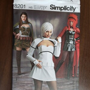 May include: Simplicity sewing pattern number 8201, size US 6, 8, 10, 12, 14, Euro 32-40, French 34-42. The pattern features three different costumes: a green and brown camouflage costume, a white and black costume, and a red and black costume.