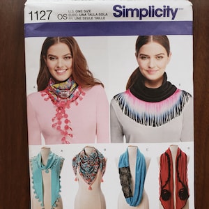 May include: Simplicity sewing pattern number 1127 for a scarf. The pattern includes instructions for five different styles of scarves, including a fringed scarf, a scarf with a lace insert, and a scarf with pom-poms. The pattern is available in one size.