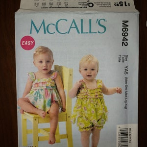 May include: A sewing pattern for a baby girl's dress. The pattern is called McCall's M6942 and is for sizes newborn to extra large. The pattern includes instructions for making a dress with a ruffle trim and a gathered skirt. The pattern is easy to follow and includes a picture of a baby girl wearing the finished dress.