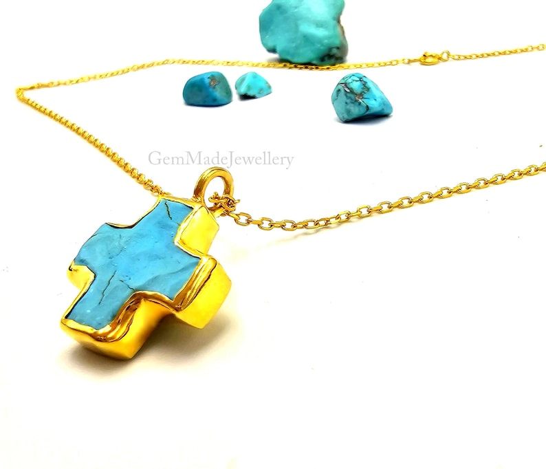 May include: A gold chain necklace with a turquoise cross pendant. The cross is made of gold and has a turquoise stone in the center. The chain is a delicate, cable chain.