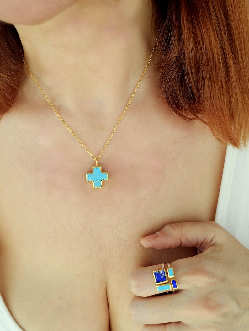 May include: A gold necklace with a turquoise cross pendant. A gold ring with turquoise and blue stones.