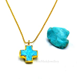 May include: A gold chain necklace with a turquoise cross pendant. The cross is made of gold and has a turquoise stone in the center. The turquoise stone is a natural stone and has a unique pattern. The necklace is a beautiful and unique piece of jewelry.