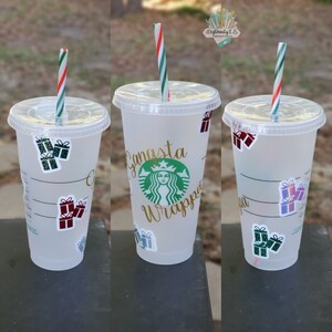May include: Three clear plastic cups with lids and red and green striped straws. The cups are decorated with festive gift box stickers and the middle cup has the text "Gangsta Wrapper" in gold lettering.