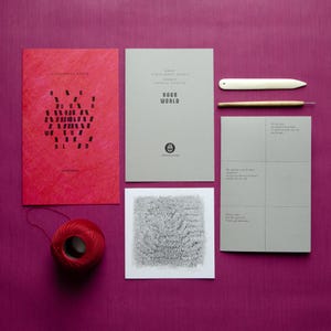 May include: A set of four items, including a red booklet with the text "Rage World" in black, a gray booklet with the text "Rage World" in black, a gray card with a black and white illustration, and a red ball of yarn.