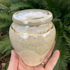 An Ancient Creations Ceramic Urn, hand made on the pottery wheel from pure clay, and hand painted with M.O.P. Available sizes suitable for human or pet ashes. Memorialize your cherished loved one with a classy and sustainably created cremation urn.