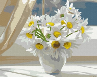 May include: A bouquet of white daisies with yellow centers in a white vase. The daisies are arranged in a vase on a white tablecloth. The vase is sitting on a windowsill with a sheer curtain in the background.