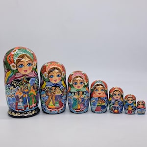 May include: A collection of seven Russian Matryoshka dolls. Each doll is painted with a unique design, the largest depicting a winter scene. The smaller dolls feature floral patterns and portraits of women, showcasing traditional artistry.