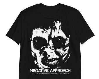 Può includere: Maglietta nera con una grafica bianca di un viso distorto e il testo "NEGATIVE APPROACH".