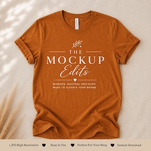 May include: A rust-colored t-shirt with rolled-up sleeves. The shirt features the text "THE MOCKUP Edits" in white, along with the tagline "MODERN, NEUTRAL MOCKUPS MADE TO ELEVATE YOUR BRAND." The image also includes the text "1 JPG High Resolution", "Easy to Use", "Perfect For Your Shop", and "Instant Download."