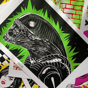 May include: Black and white illustration of an alien creature with a green starburst background. The alien has a large head and a long, thin body. The illustration is printed on a white background.