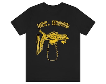 May include: Black t-shirt with a yellow graphic design. The design features the text "MT. HOOD" above a stylized illustration of a fist holding a wooden object, with a flame-like shape below.