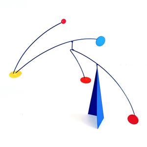 May include: A contemporary mobile sculpture with a blue triangular base and curved black rods. It features red, yellow, and blue circular and spherical elements. The artwork is set against a white backdrop.