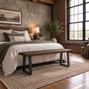 May include: A rectangular bench featuring a thick, dark brown reclaimed wood seat with a visible grain texture, supported by two sturdy, black powder-coated metal U-shaped legs. The bench is positioned horizontally in front of a bed.