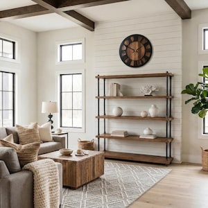 May include: A large round wall clock with a dark black frame and a brown wood-grain face featuring black Roman numerals and thin black hands, mounted on a white shiplap wall above a four-tier open shelving unit made of dark metal pipes and wood.